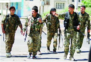 FILE PHOTO: Kurdish fighters from the People's Protection Units (YPG) walk along a street in the southeast of Qamishli city